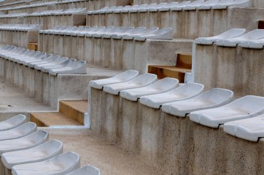 The interior of a football stadium without spectators. Seats for spectators on the stadium podium. Old worn plastic chairs for spectators of sports football matches