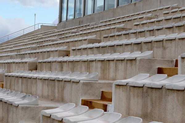 The interior of a football stadium without spectators. Seats for spectators on the stadium podium. Old worn plastic chairs for spectators of sports football matches