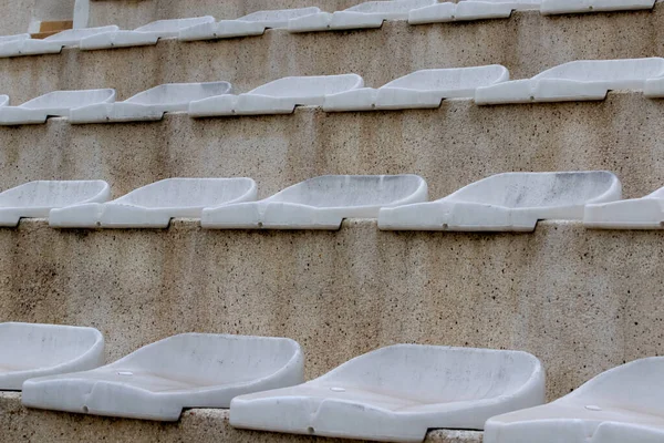 The interior of a football stadium without spectators. Seats for spectators on the stadium podium. Old worn plastic chairs for spectators of sports football matches
