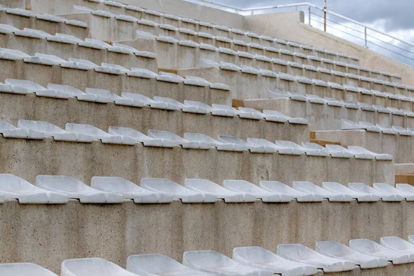 The interior of a football stadium without spectators. Seats for spectators on the stadium podium. Old worn plastic chairs for spectators of sports football matches