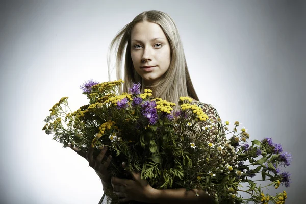 De mooie jonge vrouw met een boeket van wilde bloemen in handen — Stockfoto