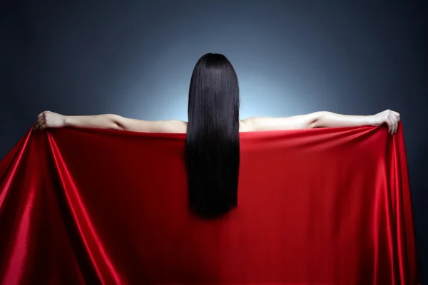 Beautiful girl back holding red fabric on black background — Stock Photo, Image