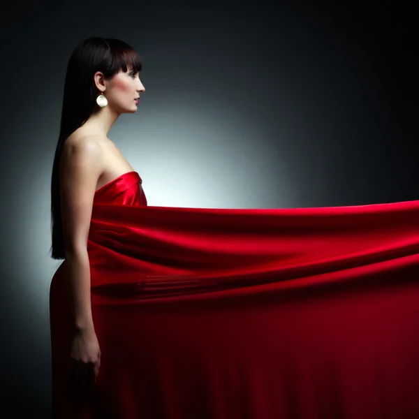 Menina bonita em vestido vermelho de volta no fundo preto — Fotografia de Stock