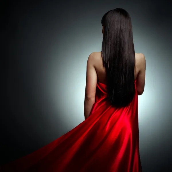 Bella ragazza in abito rosso indietro su sfondo nero — Foto Stock
