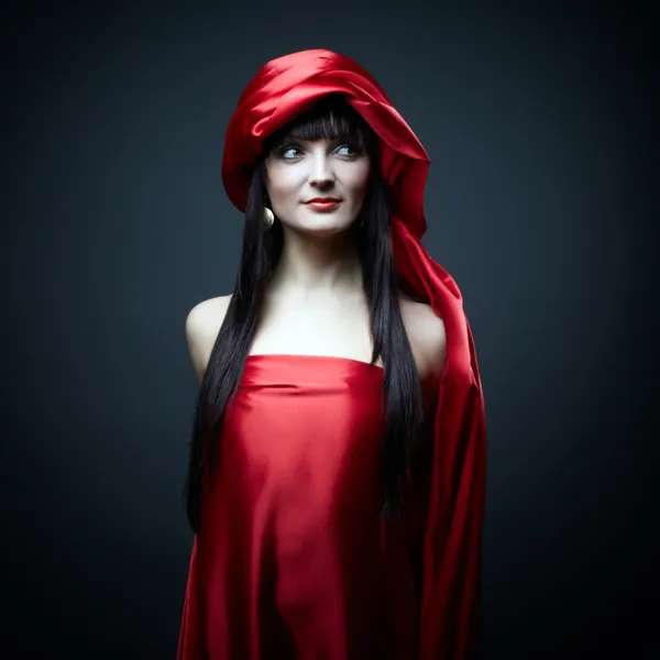 Красива дівчина сміється в червоній сукні на чорному тлі — стокове фото