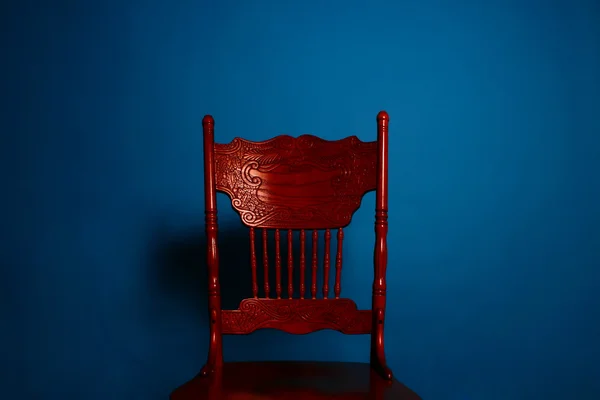 Червоний стародавній стілець на тлі темно-синьої стіни — стокове фото