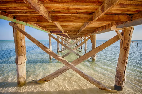 Parte inferior de un embarcadero de madera en el mar tropical —  Fotos de Stock