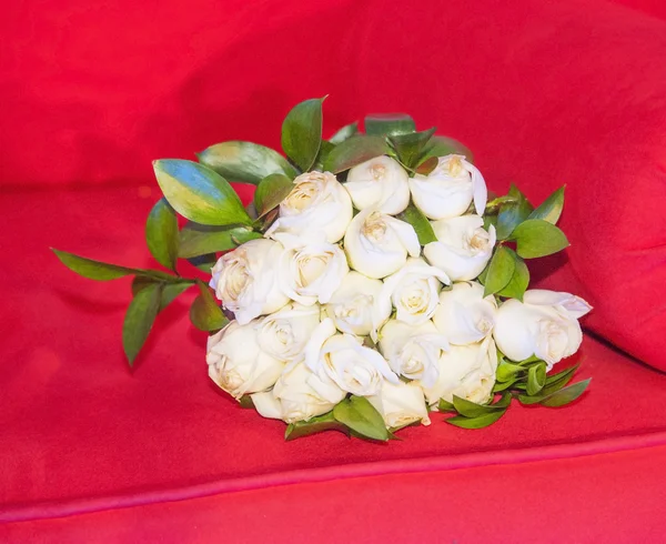 Bouquet di rose bianche su un divano rosso — Foto Stock