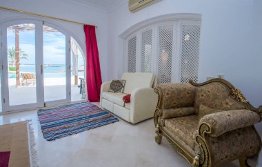 Lüks tatil köşkündeki oturma odası iç dekorasyon dekorasyonu ve tropikal deniz manzarasını gösteren evi gösteriyor.