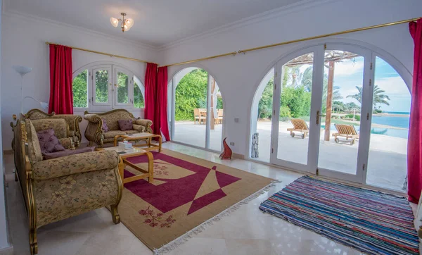 Lüks tatil köşkündeki oturma odası iç dekorasyon dekorasyonu ve tropikal deniz manzarasını gösteren evi gösteriyor.