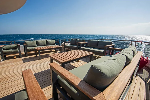大型豪华游艇的纤细船尾木制甲板 有沙发桌和热带海景背景 — 图库照片