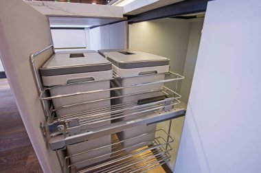 Lüks apartmandaki mutfağın iç tasarım dekoru. Çöp kutularıyla dolap sürgüsünün yakın çekimini gösteriyor.