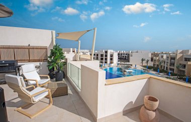 Tropikal bir tatil köyünde yüzme havuzu manzaralı bir teras mobilyası.