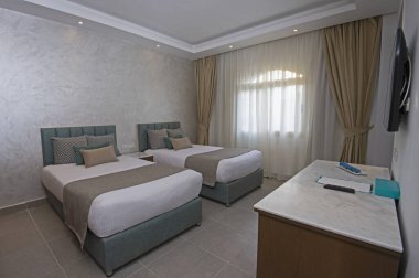Modern iç dekorasyon mobilyaları olan lüks bir otel odasındaki ikiz yataklar.