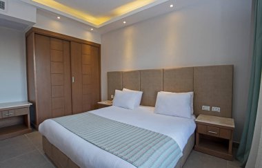 Modern mobilya iç dekorasyonlu lüks bir otel odasında çift kişilik yatak.