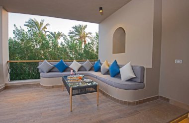 Lüks tropikal otel otelindeki teras alanında kanepe oturma alanı kokteyl içecekleri ve kanepeleri var.