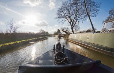 İngiliz ağaç kaplı su yolu kanalında İngiliz kırsal kırsal sahne demirlemiş dar tekneler ile tekne yay görünümü