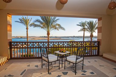 Tropikal tatil köyünde, balkondan deniz manzaralı, mobilyalı lüks bir apartmanın teras mobilyaları.