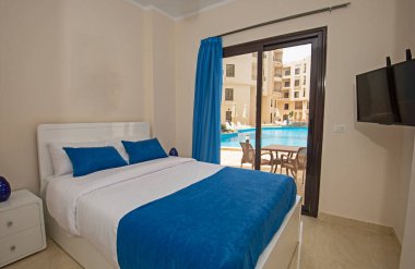 Lüks mobilyaların iç dizayn dekorasyonu ev odası mobilyaları ve yüzme havuzu manzaralı çift kişilik yatakları gösteriyor.