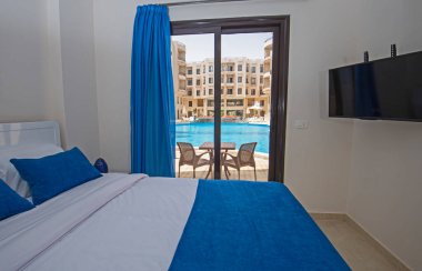 Lüks mobilyaların iç dizayn dekorasyonu ev odası mobilyaları ve yüzme havuzu manzaralı çift kişilik yatakları gösteriyor.