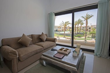 Lüks tropikal tatil dubleks apartmanındaki oturma odası oturma odası iç tasarım dekorasyonunu açık tasarım döşenmiş olarak gösteren evi gösteriyor.