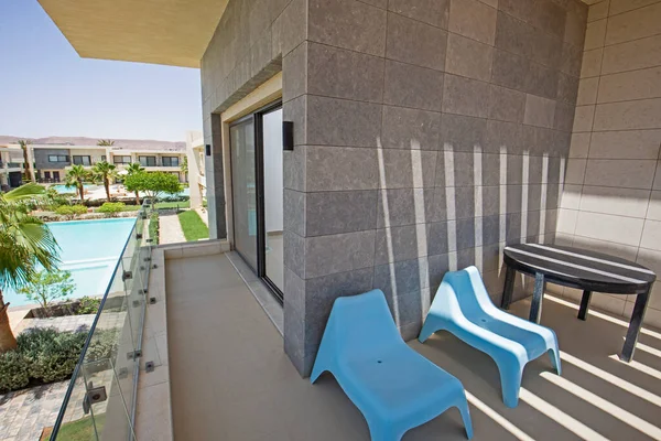 热带旅游胜地豪华公寓的平台家具 阳台和游泳池上有桌子和椅子 — 图库照片