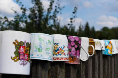 Old cups on the slats of an old fence. Traditional folk ornament. South Moravia, Czech Republic.