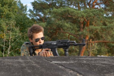 genç, savaş giysili oğlan ve bir tüfek, yumuşak hava tabancası
