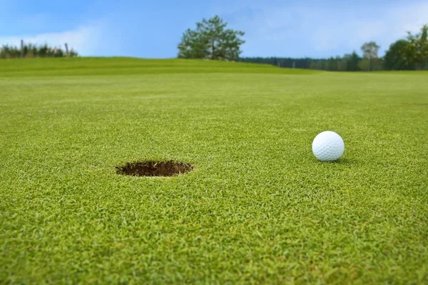 Golf, míček ležící na návsi vedle díry — Stock fotografie