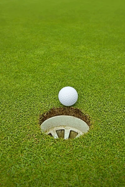 高尔夫，躺在洞口旁边绿色的球 — 图库照片