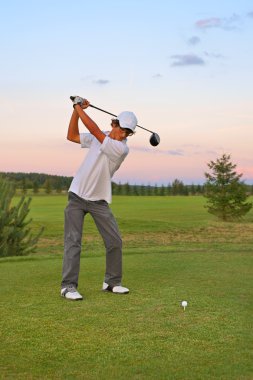 Golf topu günbatımında çarpıcı genç golfçü