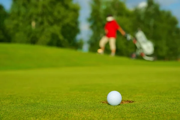 Golf, top yeşil arka delik yanında yatan golfçü gidiyor.