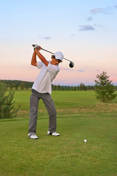 Golf, jugendlicher Golfer schlägt den Ball bei Sonnenuntergang — Stockfoto