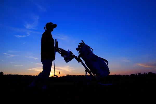 Golf, Golferin mit Golftasche bei Sonnenuntergang, als Hintergrund — Stockfoto