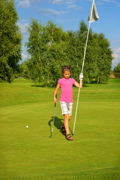 Golf, holka golfista s holí a vlajku na zelené — Stock fotografie