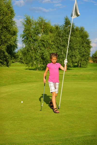 Golf, chica golfista con un palo y una bandera en el green Imagen de archivo