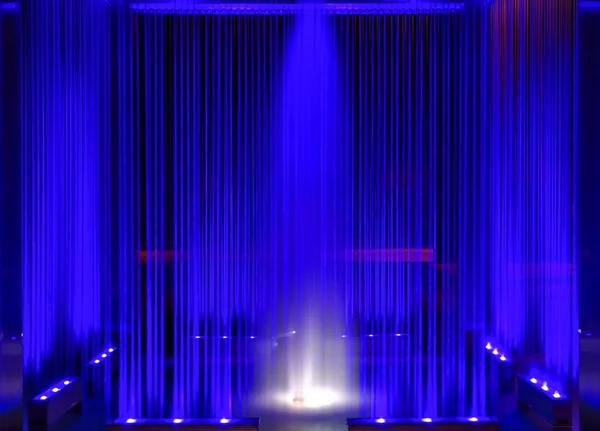 Kašna, modré osvětlené tekoucí voda v noci, abstraktní jako pozadí — Stock fotografie