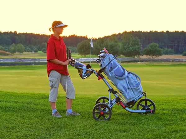 Golf, golfista donna con borsa da golf al tramonto, come sfondo — Foto Stock