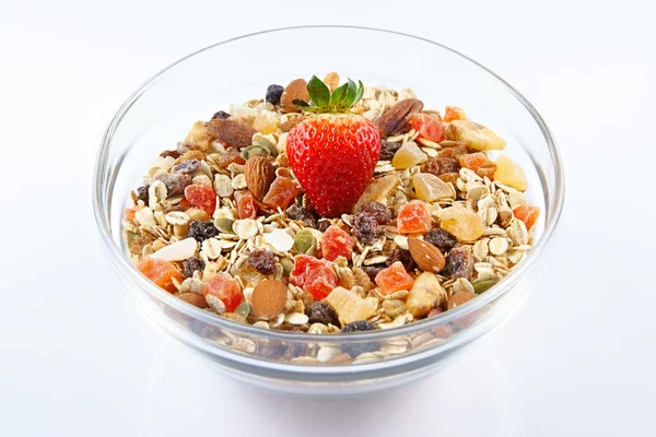 Céréales de petit déjeuner et fraises, flocons d'avoine à la fraise, fruits confits, raisins secs et noix dans un bol en verre, fond blanc — Photo