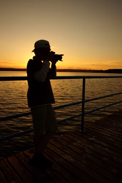 Photographer teenager and sunset over the lake — Stock Photo, Image