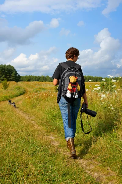 Woman photographer in the outdoors and the mascot strapped to a backpack — Stock Photo, Image