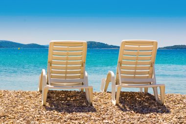 plaj sandalyeleri pebble beach, güzel mavi gökyüzü ve deniz