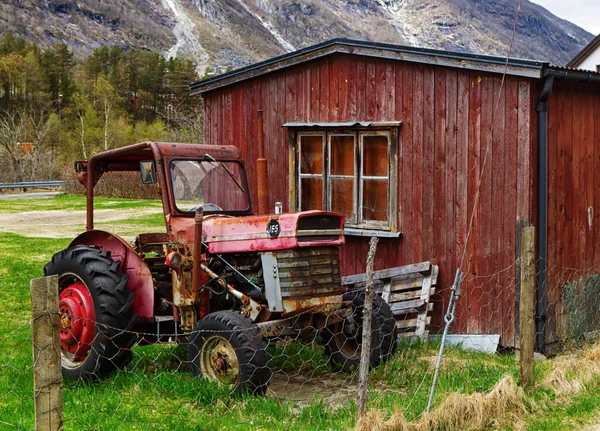 Old tractor by wooden house