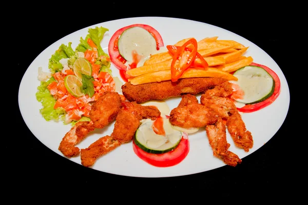 Fried frogs legs on a plate isolated in black — Stock Photo, Image