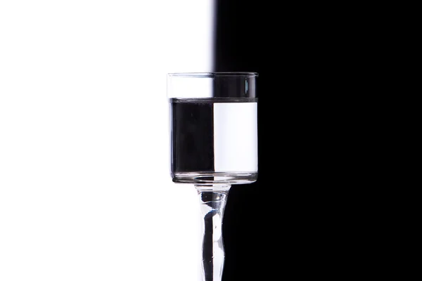 Glass with water on white and black background — Stock Photo, Image