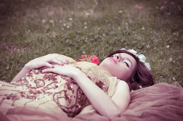 Schlafende Schönheit liegt mit einer Rose im Wald — Stockfoto