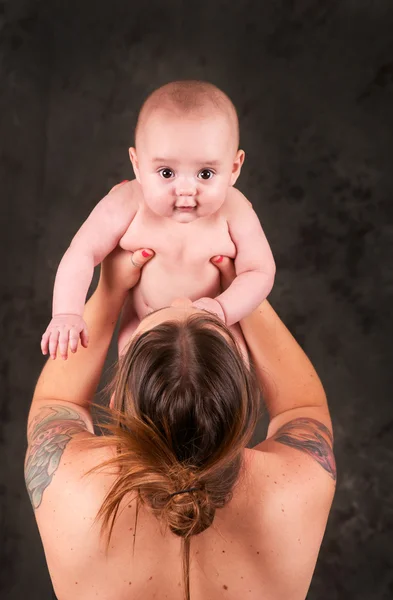 Lovely mom holding her baby up with tattoos — Stock Photo, Image