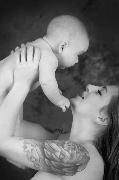 Moeder met tatoeages houden een baby kleur verwerkt — Stockfoto