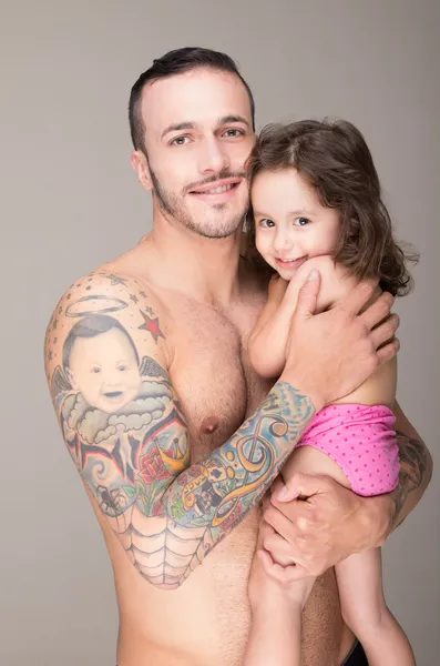 Baby op handen naar de man met een tatoeage — Stockfoto