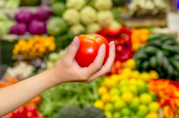 Frau hält rote Tomate im Supermarkt — Stockfoto